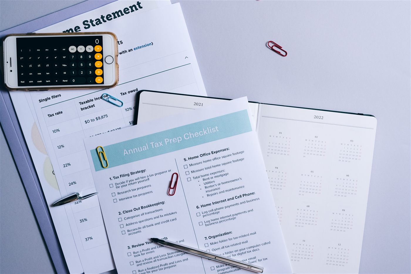 A tax prep checklist and income statement documents with a calculator